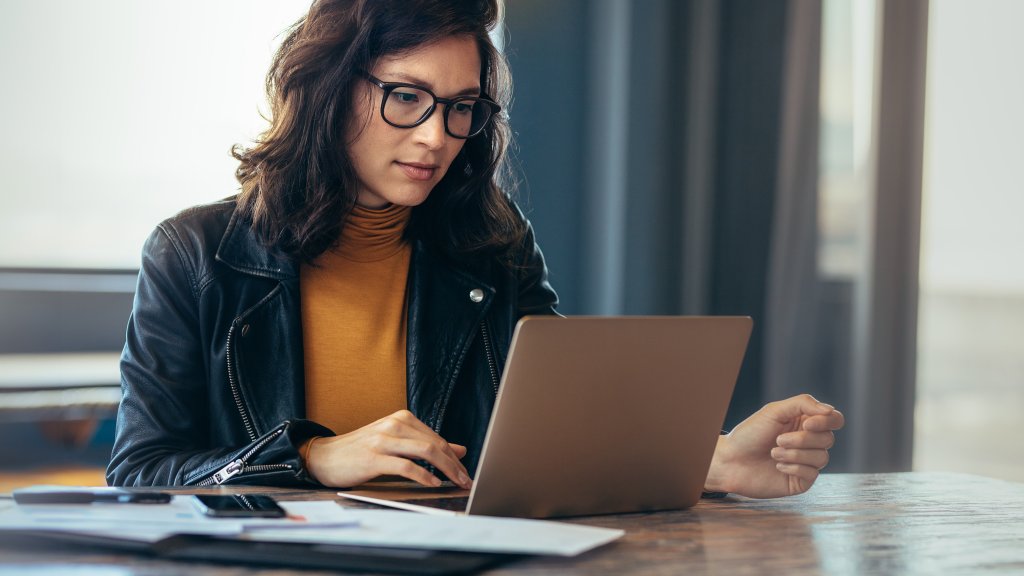 Frau im Büro arbeitet konzentriert am Laptop.
